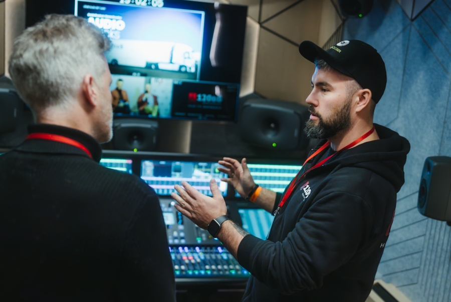 Dwóch ubranych na czarno techników muzycznych rozmawia nad panelem, służącym do poprawiania jakości dźwięku